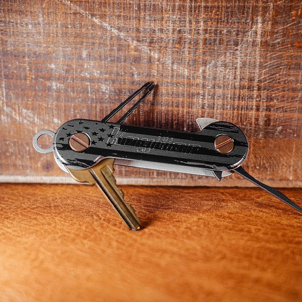 Black-and-Gray-Flag-Aluminum-UV-Printed-KeyBar-Key-and-Tool-Holder-open-front-with-titanium-pick-and-tweezers-and-aluminum-quick-key-tab