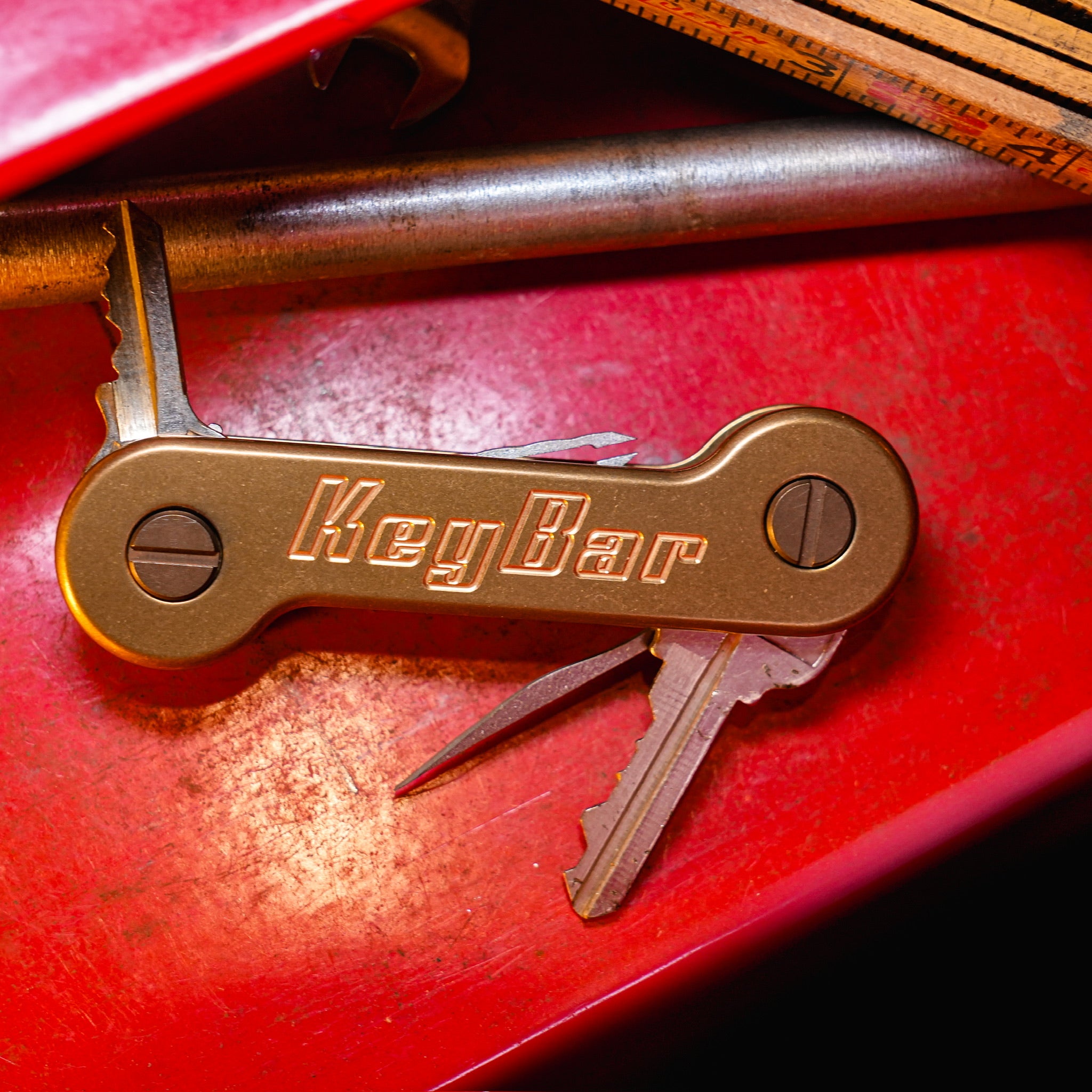 Brass KeyBar Key and Tool Holder open front on red background with keys and titanium pick