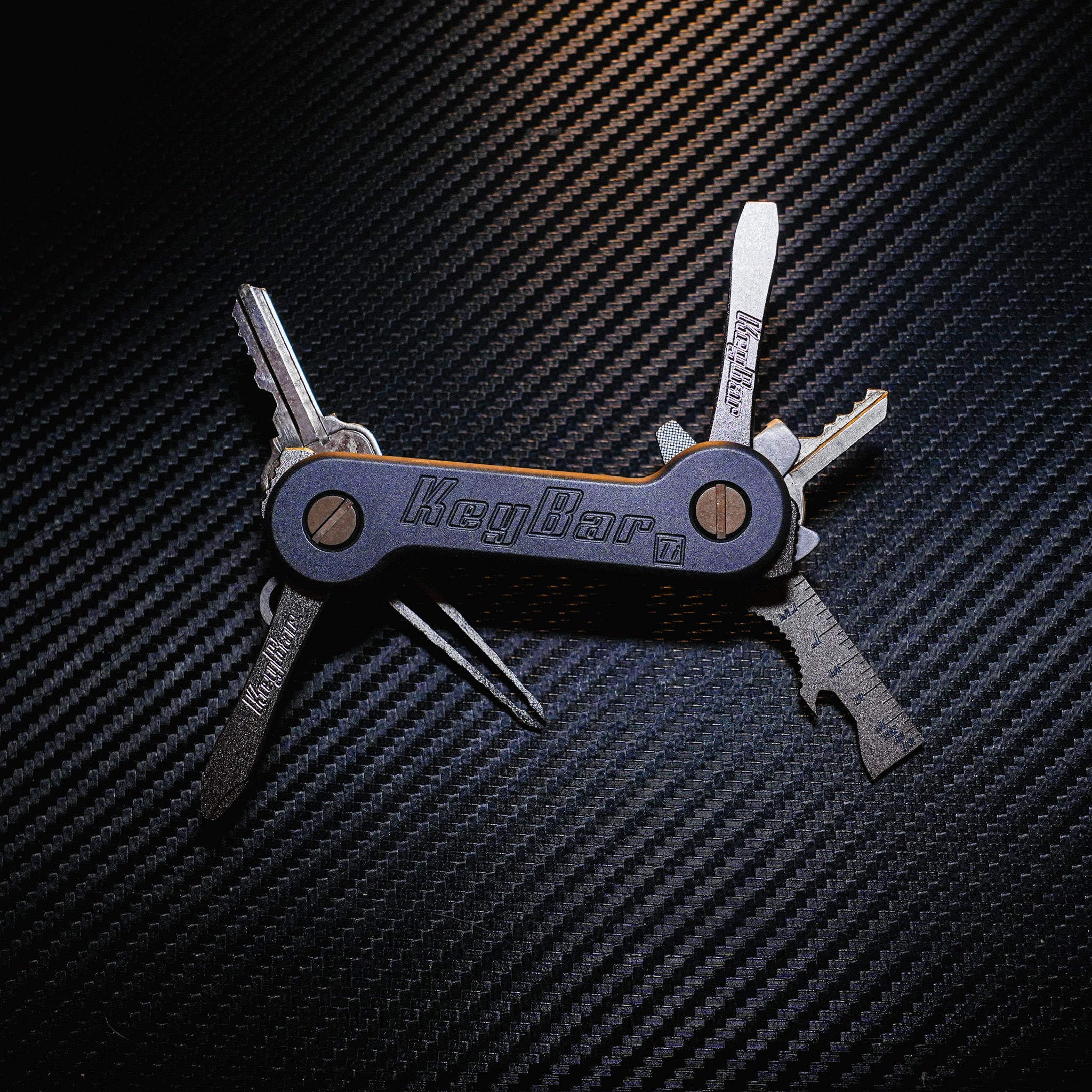 Midnight Titanium KeyBar Key Holder open front with titanium flathead screwdriver, phillips head screwdriver, multi-tool and tweezers, and aluminum quick key tab.