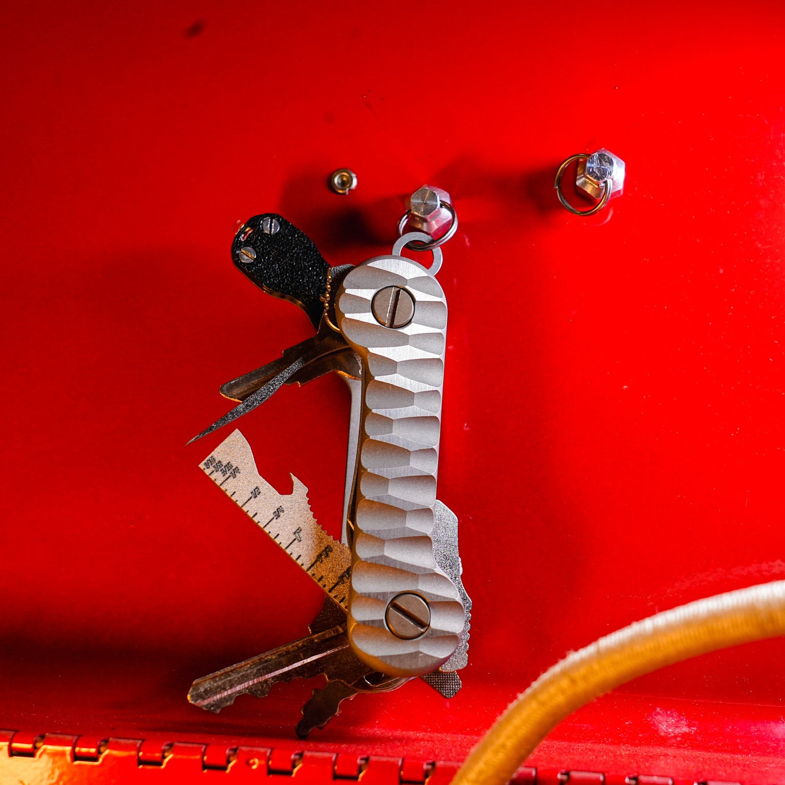 Slayer_Titanium_KeyBar_Key_and_Tool_Organizer_with_standard_titanium_pocket_clip_open_front_hanging_on_magnut_with_flashlight_multi-tool_and_pick